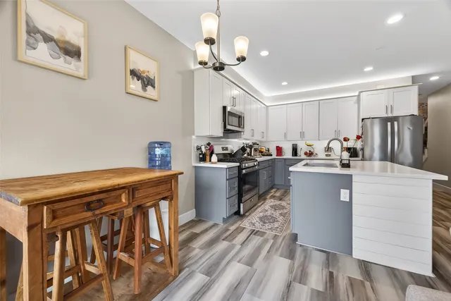 a kitchen with stainless steel appliances granite countertop a refrigerator a stove top oven a sink dishwasher and white cabinets with wooden floor