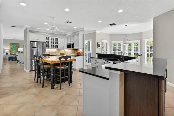 a large kitchen with lots of counter space a sink a window and chairs