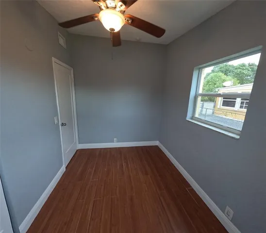 a view of an empty room with wooden floor and a window