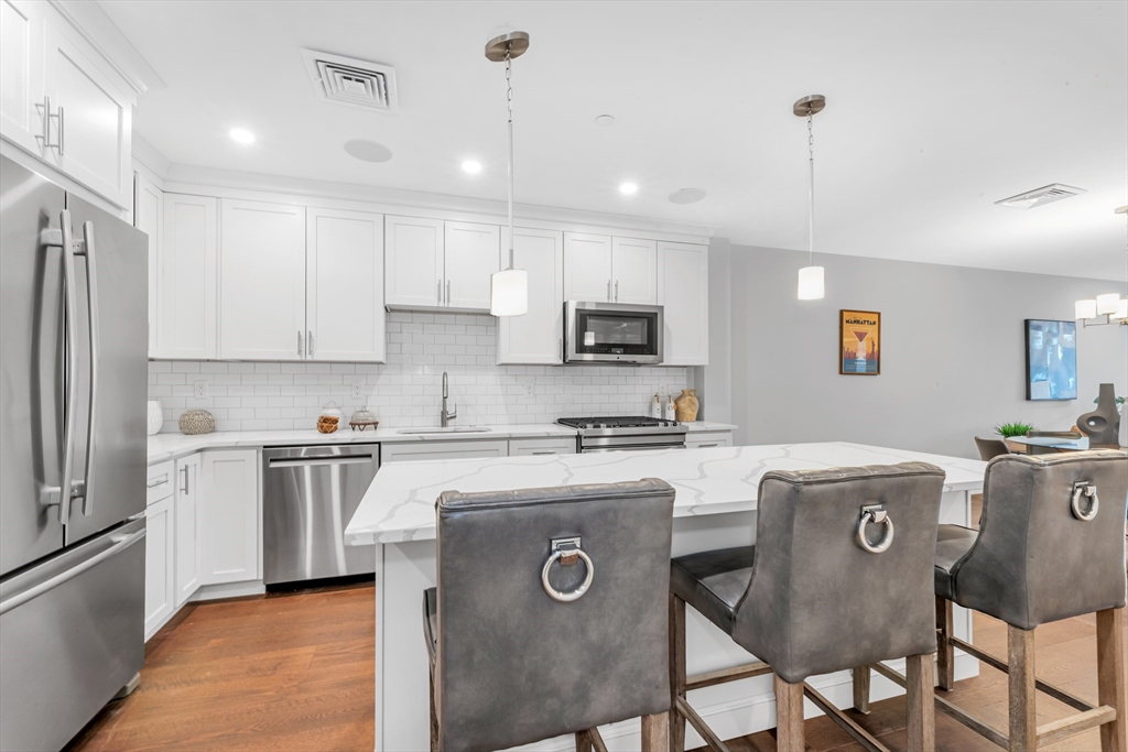 480 West Broadway, Unit 7 Boston, MA 02127 - Photo 2 of 19 a kitchen with stainless steel appliances granite countertop a dining table chairs refrigerator and sink