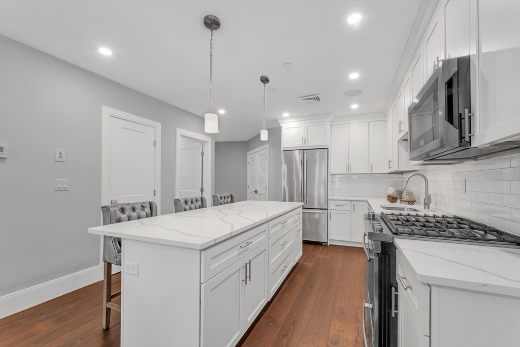 480 West Broadway, Unit 7 Boston, MA 02127 - Photo 4 of 19 a kitchen that has a lot of cabinets in it and wooden floors