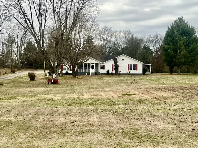 a view of a white house with a big yard and large trees