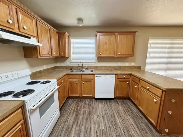 a kitchen with a white cabinets a sink dishwasher and a stove with wooden floor