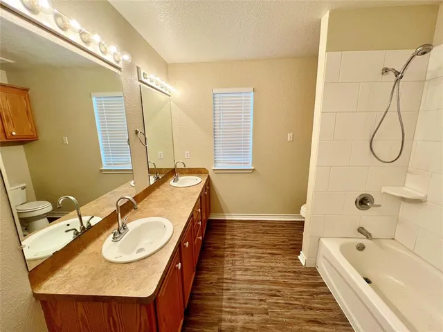 a bathroom with a sink double vanity granite tub shower and a mirror