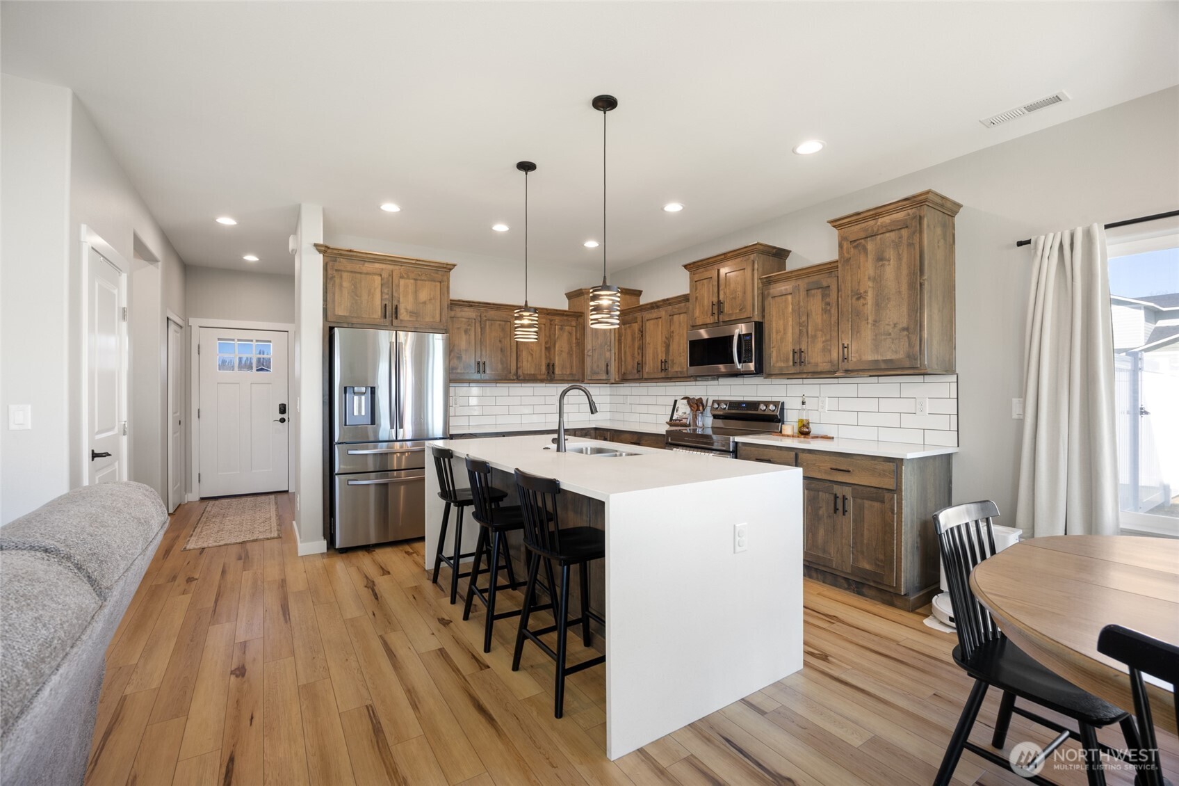 2376 Chelan Street Ephrata, WA 98823 - Photo 11 of 40 a kitchen with stainless steel appliances kitchen island granite countertop a refrigerator a stove top oven a sink dishwasher and white cabinets with wooden floor
