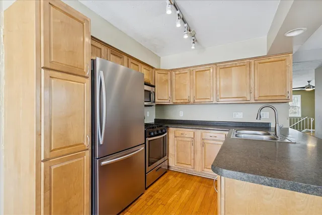 a kitchen with stainless steel appliances granite countertop a refrigerator a sink and white cabinets