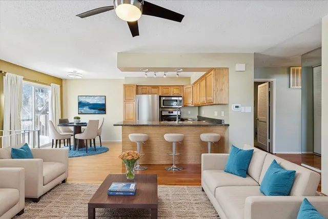 a living room with stainless steel appliances furniture a rug and a view of kitchen