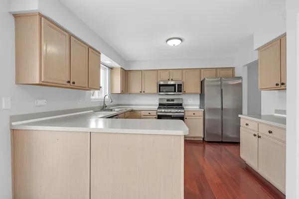 a kitchen with stainless steel appliances granite countertop a refrigerator a stove top oven a sink and dishwasher with wooden floor