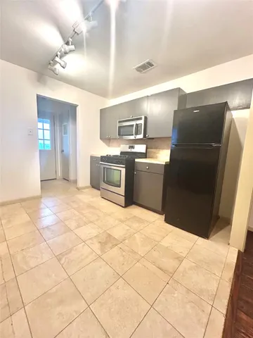 a kitchen with granite countertop a refrigerator and a stove top oven