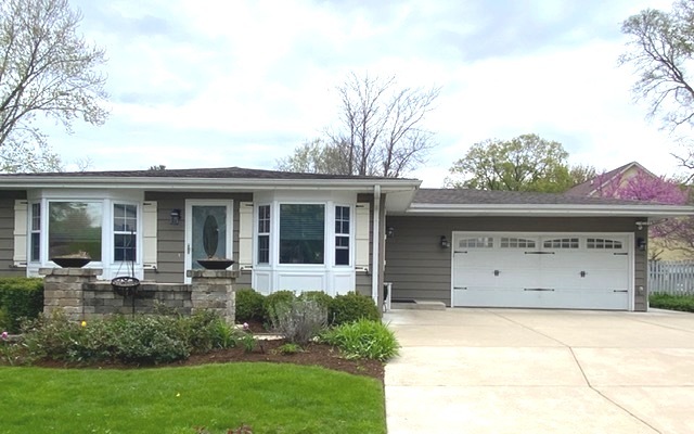 front view of a house with a garden and trees