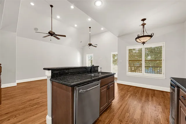a kitchen with stainless steel appliances granite countertop a stove a sink a window and wooden floor
