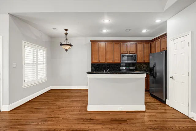 a view of kitchen with kitchen island wooden floors appliances and cabinets