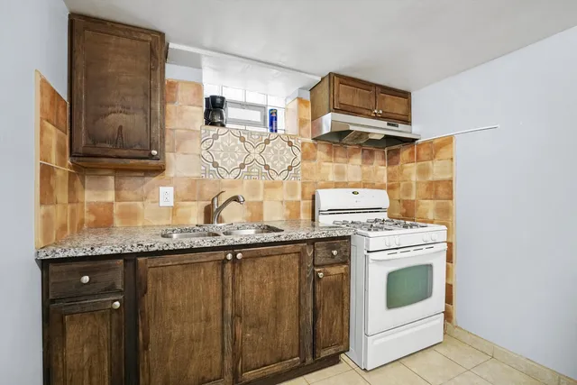 a kitchen with granite countertop a sink and a stove top oven