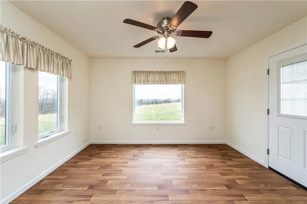 a view of a room with a ceiling fan and wooden floor