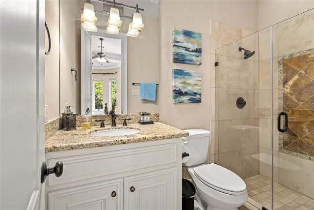 a bathroom with a granite countertop sink toilet mirror and shower