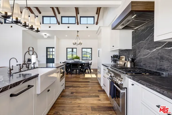 a large white kitchen with stainless steel appliances granite countertop a stove and a sink