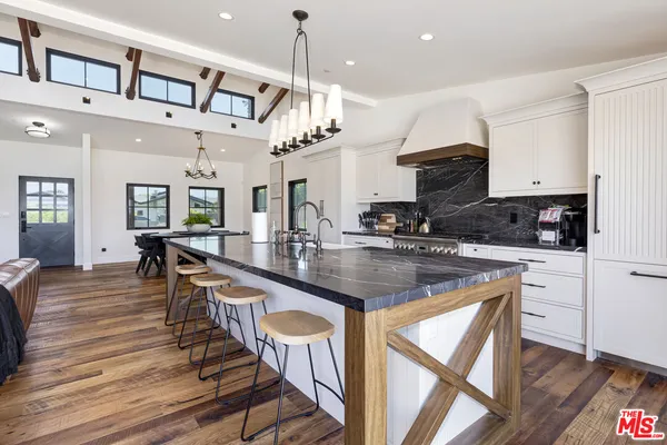an open kitchen with granite countertop a stove a sink a dining table and chairs with wooden floor