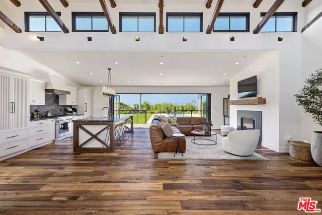 a living room with fireplace furniture and a kitchen view