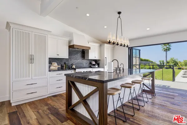 a kitchen with stainless steel appliances granite countertop a table chairs and a refrigerator