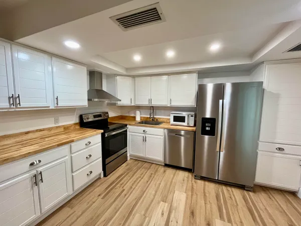 a kitchen with white cabinets stainless steel appliances and wooden floor