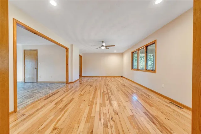 a view of an empty room with window and wooden floor