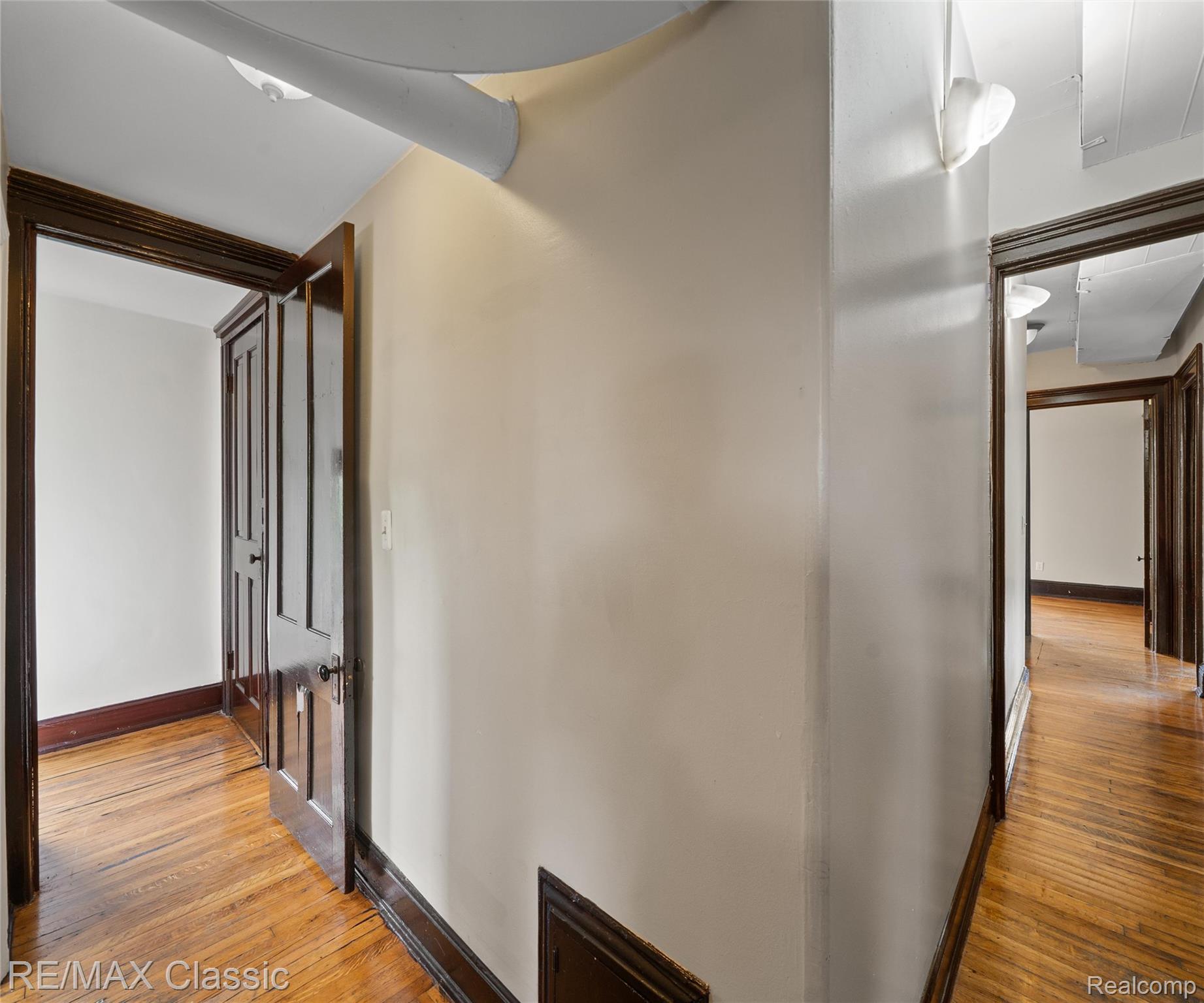 3941 Trumbull Detroit, MI 48208 - Photo 9 of 46 Hallway featuring wood-finish flooring, dark wood trim, paneled doors, and wall-mounted light fixtures