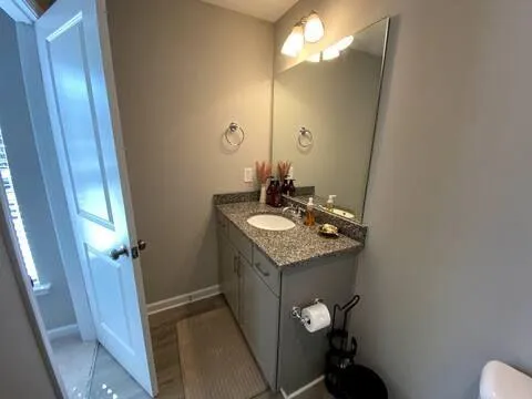 a bathroom with a granite countertop sink a toilet and a mirror