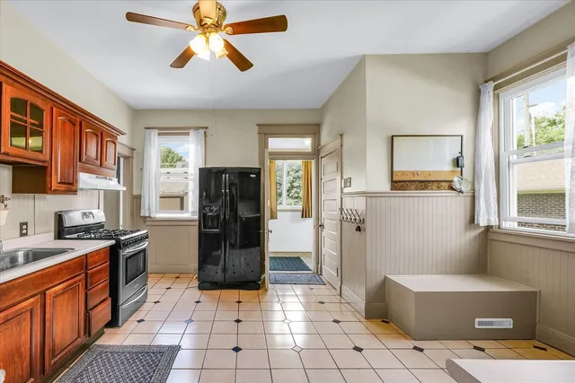 a kitchen with stainless steel appliances a refrigerator a stove a sink a dining table and chairs with wooden floor