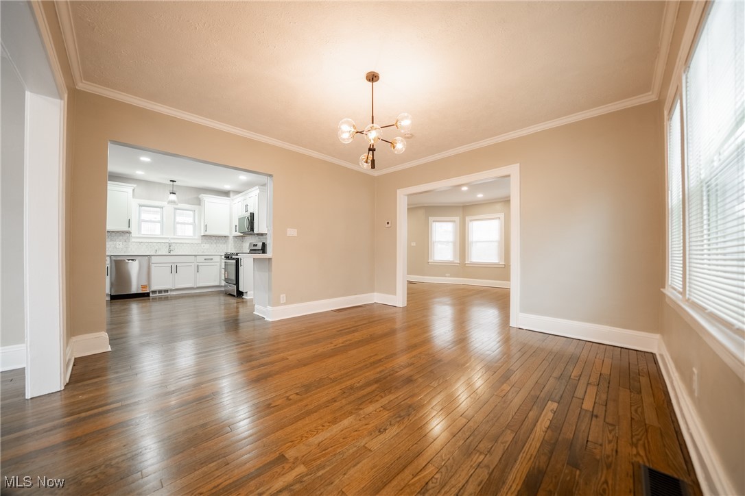 3816 Summit Park Road Cleveland Heights, OH 44121 - Photo 6 of 35 Unfurnished living room featuring a chandelier, ornamental molding, and dark wood-style floors