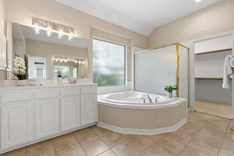 a spacious bathroom with a tub sink and mirror
