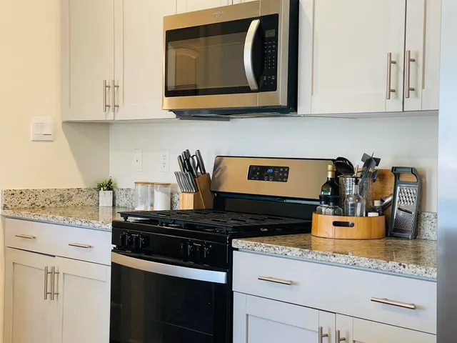 a kitchen with granite countertop white cabinets and black appliances