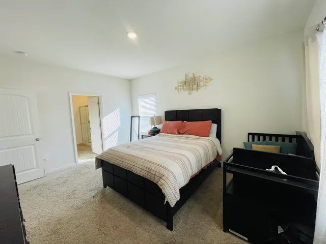 a bedroom with a bed and a flat tv screen on a dresser