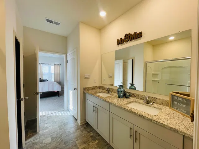 a bathroom with a granite countertop sink a mirror and shower