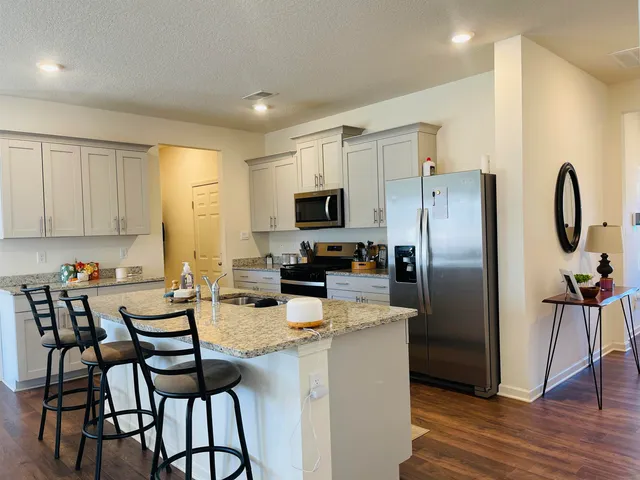 a kitchen with granite countertop a refrigerator and a stove top oven
