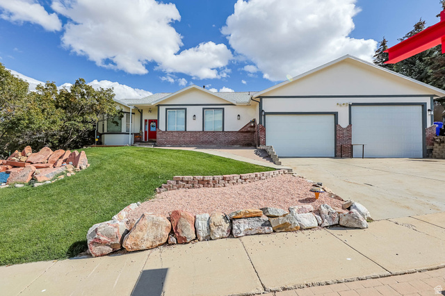 569 Elk Meadow Loop Tooele, UT 84074 - Photo 1 of 56 Single story home with stucco siding, brick siding, a front lawn, concrete driveway, and an attached garage