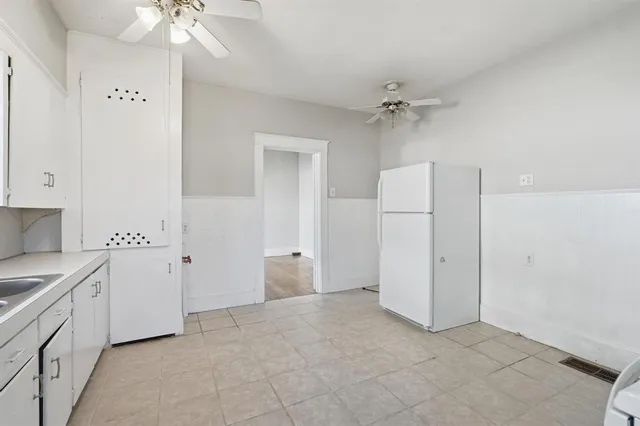 an empty room with a ceiling fan and white walls