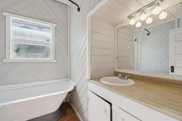 a bathroom with a tub a sink and mirror