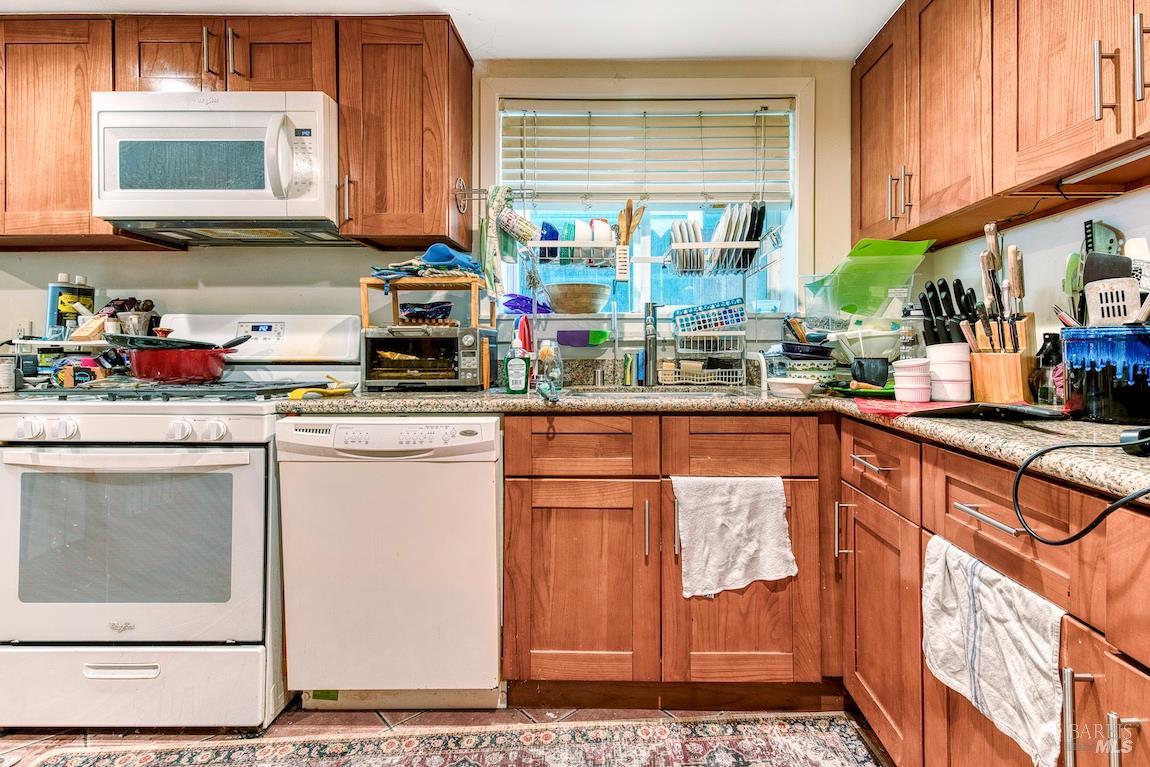 1128 Chester Street Oakland, CA 94607 - Photo 32 of 42 a kitchen with stainless steel appliances kitchen island granite countertop a refrigerator and a stove top oven