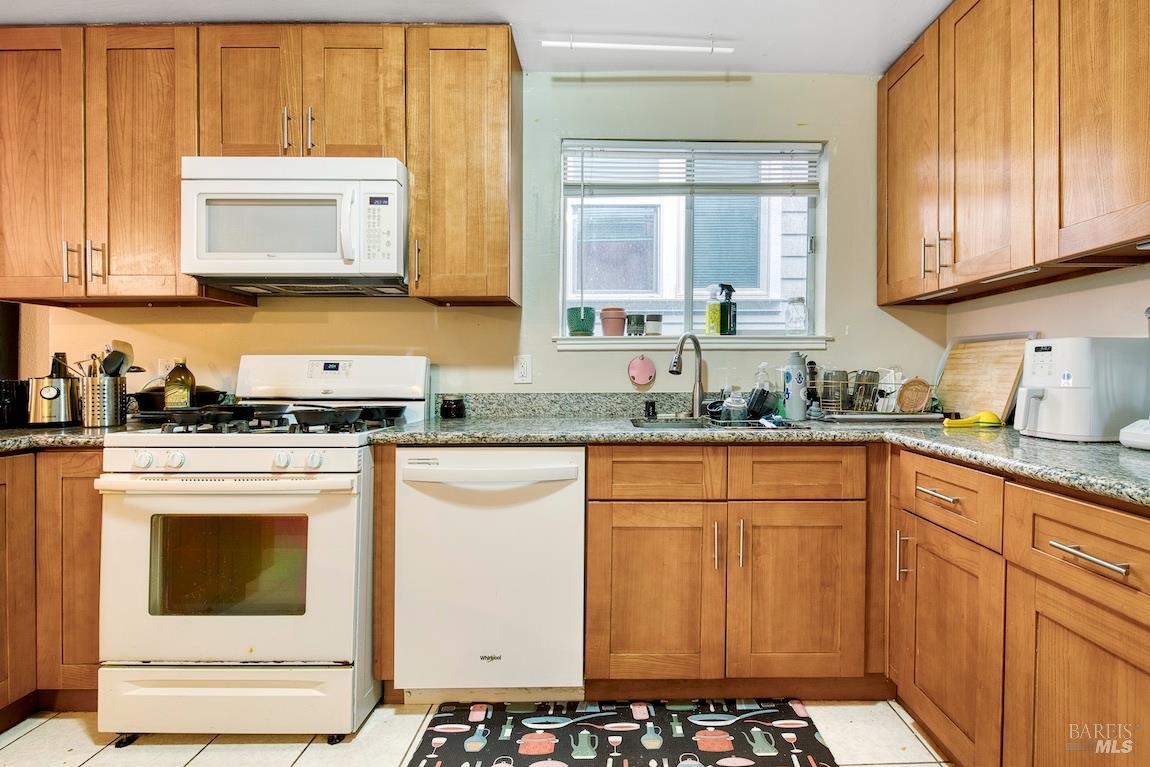 1128 Chester Street Oakland, CA 94607 - Photo 9 of 42 a kitchen with granite countertop white cabinets and white appliances