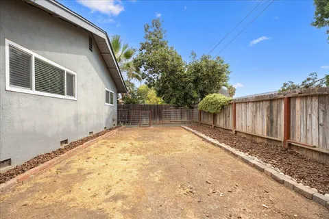 a view of backyard with wooden fence and trees