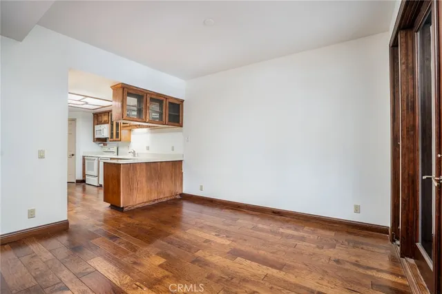 a kitchen with stainless steel appliances granite countertop a refrigerator a sink dishwasher a stove and white countertops with wooden floor