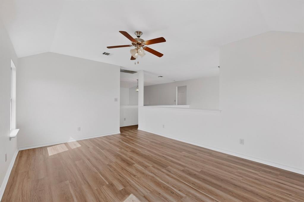 426 Harding Lane Lavon, TX 75166 - Photo 33 of 40 Spacious room featuring vaulted ceilings, wood-finish flooring, a ceiling fan with integrated lighting, and white painted walls