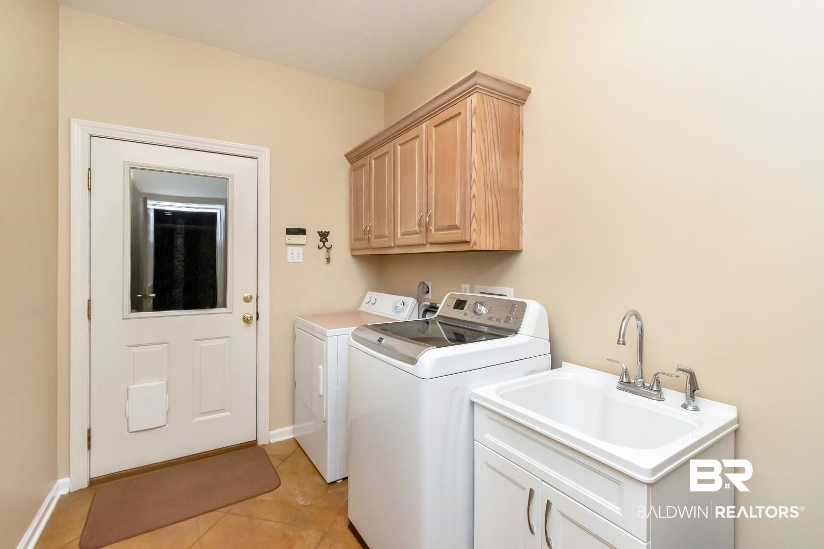 1050 Southern Way Court Mobile, AL 36609 - Photo 28 of 36 Laundry room featuring sink, light tile patterned floors, cabinets, and independent washer and dryer