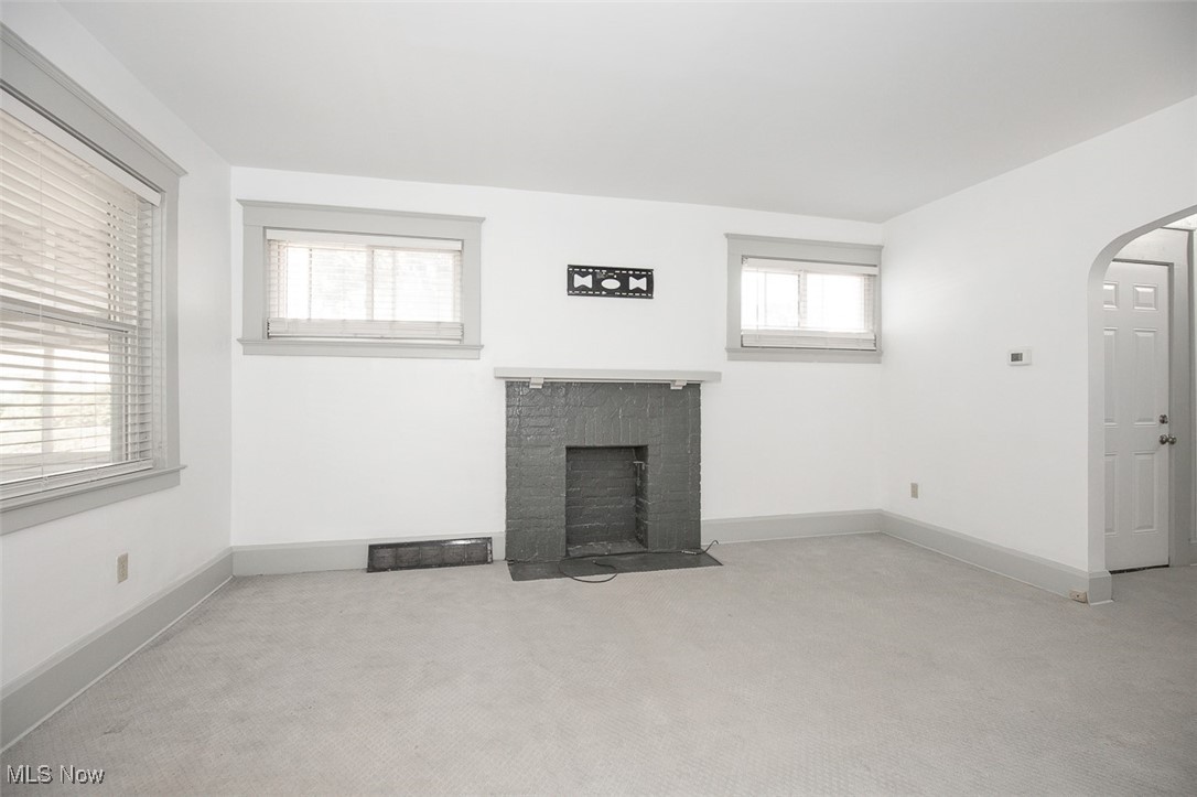 1604 Hampton Road Akron, OH 44305 - Photo 14 of 30 Unfurnished living room with arched walkways, a fireplace with flush hearth, and light carpet