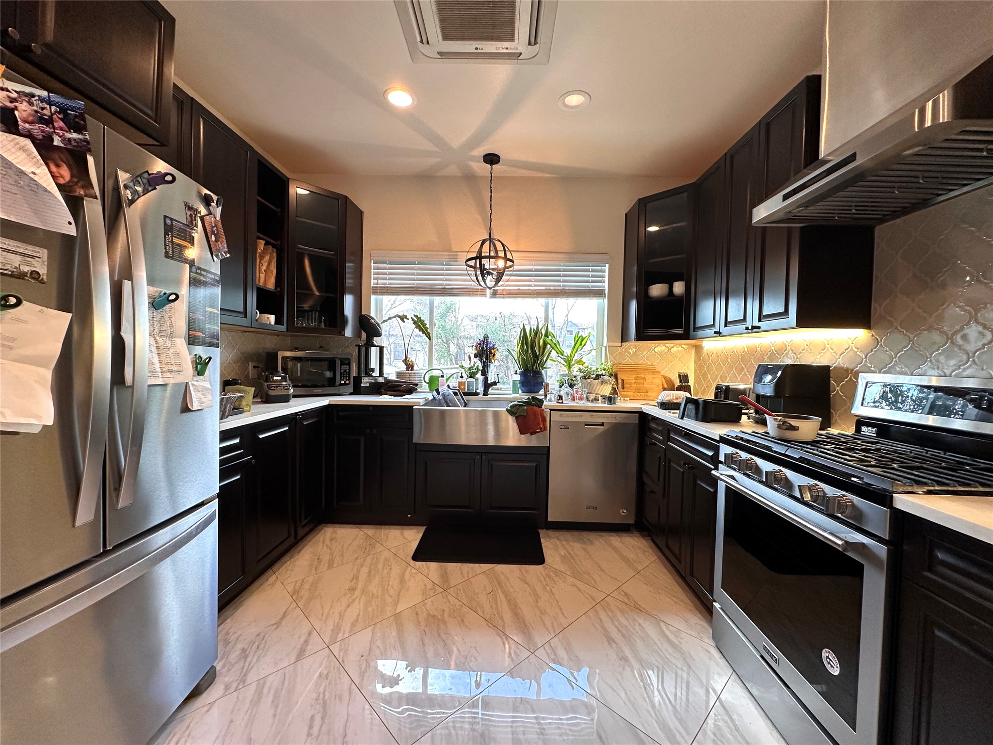 5004 Rowena Avenue, Unit A Austin, TX 78751 - Photo 11 of 24 a kitchen with stainless steel appliances kitchen island granite countertop a refrigerator a sink dishwasher a stove and a dining table with wooden floor