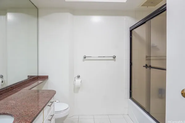 a bathroom with a granite countertop toilet a sink and a mirror