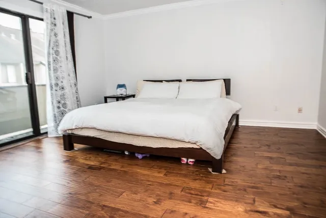 a spacious bedroom with a bed and wooden floor