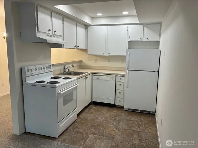 a kitchen with stainless steel appliances granite countertop a sink stove a refrigerator and white cabinets
