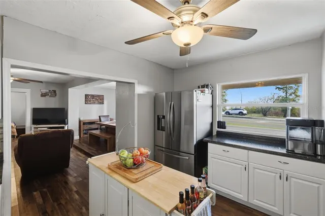 a kitchen with a refrigerator a stove a sink and living room view