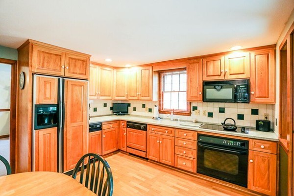 67 Bare Hill Road Topsfield, MA 01983 - Photo 3 of 22 a kitchen with stainless steel appliances granite countertop a refrigerator a sink dishwasher a stove and a dining table with wooden cabinet